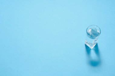 Kağıt üzerinde bir bardak su. Gölgeler çiziyor. Klasik mavi renk. Temiz su kavramı