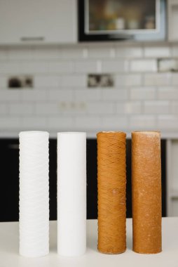 Kullanılan su filtresi kartuşu ve bir bardak kirli su ve yeni saf filtre ile kithen arka planında bulunan yerli osmoz sistemlerinden bir bardak temiz su. Su tedavisi kavramı.