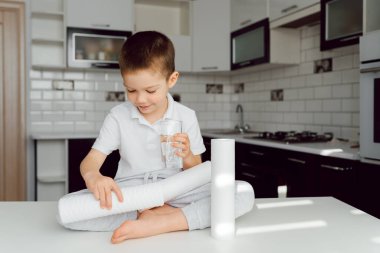Çocuk mutfakta bir bardak arıtılmış suyla bekliyor. Evde temiz su kavramı. Ev suyu filtrelerini kullan. Temiz su sağlığın anahtarıdır.