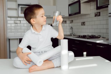 Mutfaktaki küçük bir çocuk bardaktan temiz su içer, temiz su sağlığın teminatıdır. Su arıtma konsepti. evde su filtresi kullanımı