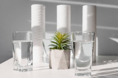 Ev Filtreleme Sistemi kavramı. Su arıtma konsepti. Evde su filtresi kullanılıyor. Beyaz arka planda temiz su ve filtreler.