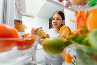 Açık buzdolabının önünde sebzeli mutlu bir kadın. Evde sağlıklı beslenme kavramı