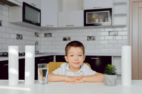 Cute little boy drinking water in kitchen. water treatment concept. kitchen water filters and clear water