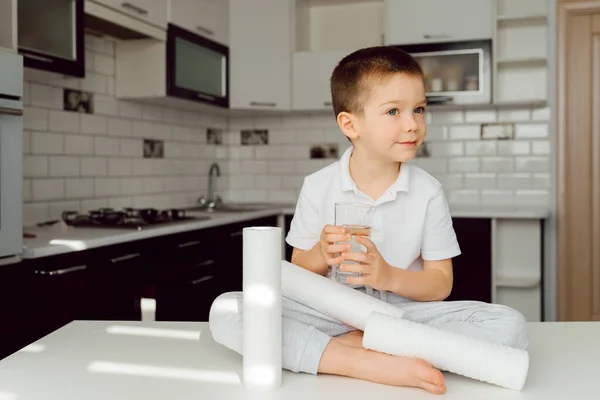 boy in the kitchen with a glass of purified water. clean water concept at home. Use home water filters. Clean water is the key to health