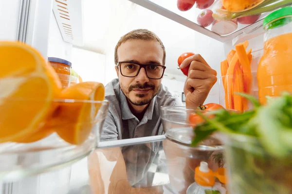 Look in the fridge. Young and successful couple in love looks in the fridge and take out of the fridge a bottle of milk while standing in the kitchen and makes breakfast.