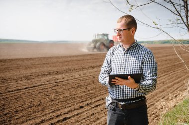 Tarlada çiftçi. Ellerinde tohum ekiyor ve tableti tutuyor..