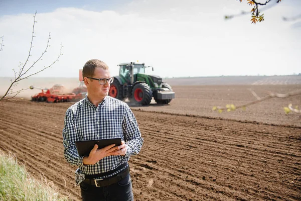 farmer on background of tractor sowing field. Work in the field. Agriculture concept. Farm work in the field in spring