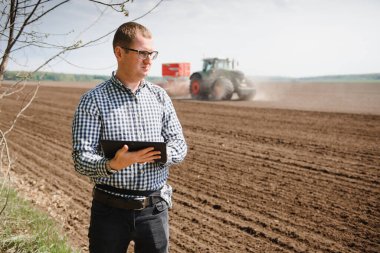 Tarlada çiftçi. Ellerinde tohum ekiyor ve tableti tutuyor..