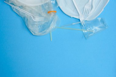 Mavi arka planda beyaz plastik. Plastik kirliliği. Geri dönüşüm plastiği, yeniden kullanılabilir paketler, çöp konsepti. Sıfır atık, ekoloji. Kopyalama,