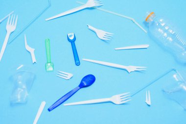 Beyaz tek kullanımlık plastik, mavi arka plandaki çöp kutusunda. Plastiği geri dönüştürme kavramı. Düz yatış, üst görünüm