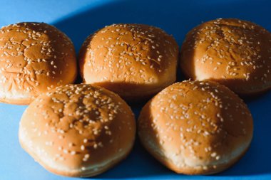 Hamburger ekmeği izole edilmiş. Mavi arka planda izole edilmiş Amerikan yemekleri klasik yuvarlak hamburger ekmeği. Izgara hamburger ekmeği. Yakın plan..