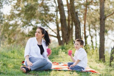 Huysuz anne ve yakışıklı oğul doğada eğleniyor. Mutlu aile kavramı. Aile hayatı olan güzel doğa manzarası. Mutlu bir aile birlikte dinleniyor. Aile yaşamında mutluluk. Anneler Günü.