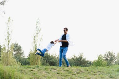 Baba ve oğul doğada birlikte eğleniyorlar. Baba oğul oynuyor. İnsanlar dışarıda eğleniyor. Arkadaş canlısı aile kavramı.