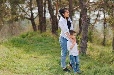 Mutlu genç anne bebeğiyle yeşil bir çimenlikteki parkta oynuyor. Aile hayatının mutluluğu ve ahengi. Harika bir aile tatili. İyi hafta sonları Anneler Günü. Tatil günü. Mutlu aile kavramı..