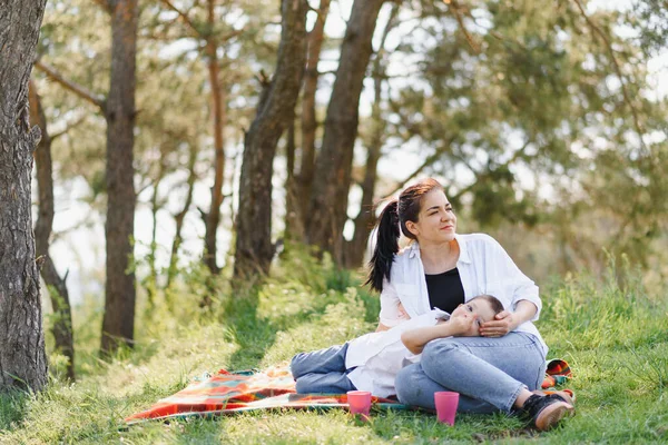 快乐的年轻母亲正在一个绿色草坪上的公园里和她的孩子玩耍 家庭生活的幸福与和谐 家庭度假愉快 周末好母亲节 幸福家庭的概念 — 图库照片