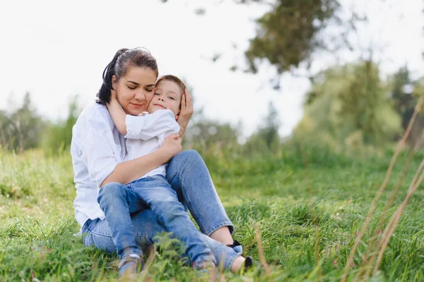 快乐的年轻母亲正在一个绿色草坪上的公园里和她的孩子玩耍 家庭生活的幸福与和谐 家庭度假愉快 周末好母亲节 幸福家庭的概念 — 图库照片
