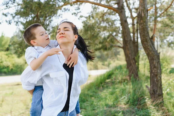 Kiss and hugs of mom and son. Mom and son walk in the summer park. Family holiday and togetherness. Happy mother\'s day.