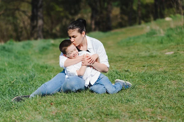 Kiss and hugs of mom and son. Mom and son walk in the summer park. Family holiday and togetherness. Happy mother\'s day.