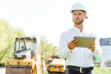 Yol makinelerinin yanında mühendis. Yeni bir asfalt yol yapma fikri. Yol tamiri. Pistin yakınında bir yol işçisi..