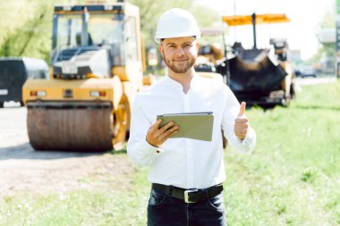 Yol inşaatçıları asfalt kaldırım makinesinin yanında. Yol tamiri. Pistin yakınında bir yol işçisi..