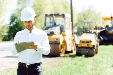 Yol inşaatçıları asfalt kaldırım makinesinin yanında. Yol tamiri. Pistin yakınında bir yol işçisi..