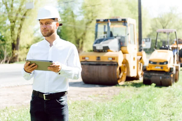 engineer near road machinery. The concept of building a new asphalt road. Road repair. Road service worker near the rink.