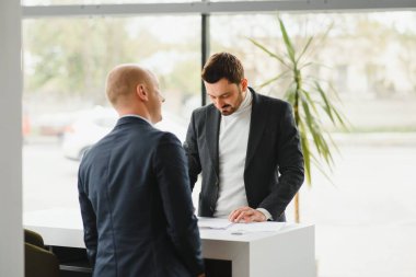 Gösteri odasındaki genç yakışıklı adam arabanın yanında duruyor.