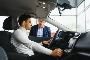 Güzel iş konuşması. Yakışıklı genç işadamı akıllı telefonuyla konuşuyor ve ön koltukta otururken gülümsüyor.