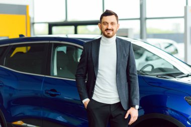 Yakışıklı bir adam gösteri odasında araba seçiyor.