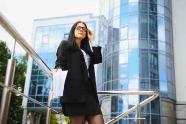 Modern bir binanın yakınındaki bir iş toplantısında belgeli bir kız.