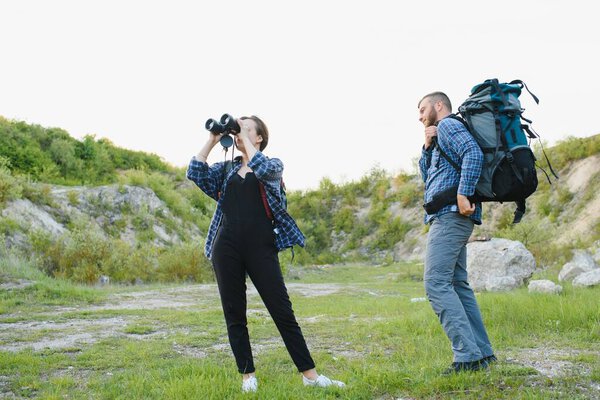 A couple of tourists in time of trip steel and admire the beautiful mountain scenery. The guy hugs the girl. The concept of love, tenderness and recreation