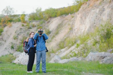 Sırt çantalı yürüyüşçüler tepenin üstünde dinleniyor ve okyanusta günbatımının keyfini çıkarıyorlar. Lombok Adası, Endonezya. Dağlar ve kıyı boyunca seyahat, özgürlük ve aktif yaşam tarzı konsepti