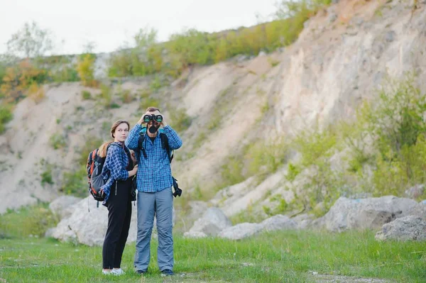 Sırt çantalı yürüyüşçüler tepenin üstünde dinleniyor ve okyanusta günbatımının keyfini çıkarıyorlar. Lombok Adası, Endonezya. Dağlar ve kıyı boyunca seyahat, özgürlük ve aktif yaşam tarzı konsepti