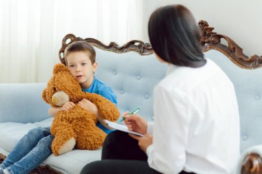 Ofiste küçük bir çocukla çalışan genç bir psikolog.
