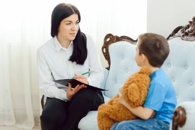 Çocuk psikoloğu küçük bir çocuğa bakıyor. Çocuklara psikolojik yardım kavramı.