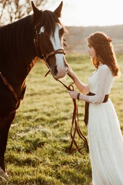 Gün batımında arka planda bir atı olan güzel bir gelin. At ile poz veren bir kız
