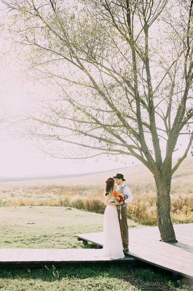 Bride and groom posing under a large tree against the background of the river. rustic. loft — Stock Photo, Image