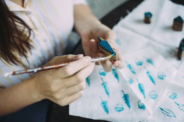 Üstat kız kumaşa pul yapıştırıyor. El yapımı.