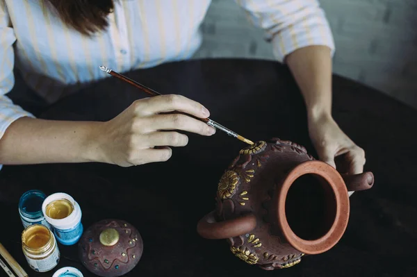 Meisje kunstenaar schildert een klei theepot in haar atelier. Creativiteit. Handwerk. Kunst. Zelfstandigen — Stockfoto
