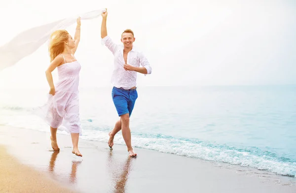 Feliz pareja corriendo en la playa — Foto de Stock