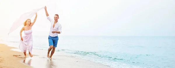 Happy couple running on the beach — Stock Photo, Image