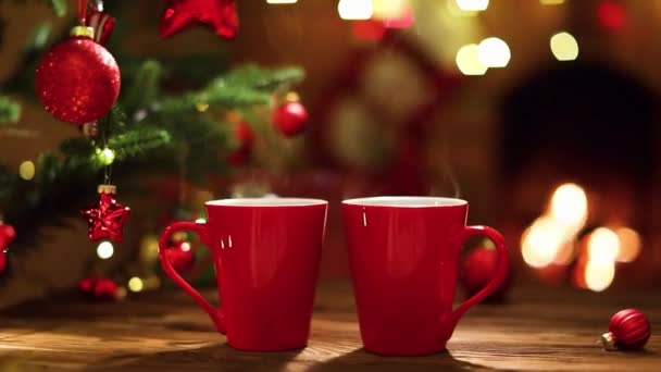 Decoraciones de Navidad y tazas rojas de café en el fondo de la chimenea — Vídeo de stock