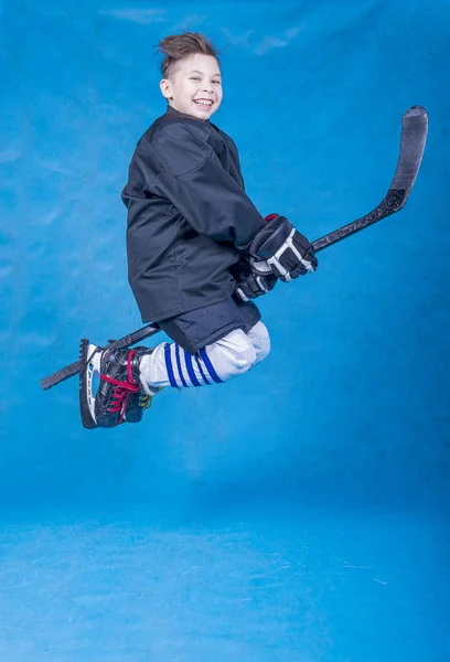 陽気若いですホッケー選手飛行上のホッケースティック上の青の背景 — ストック写真