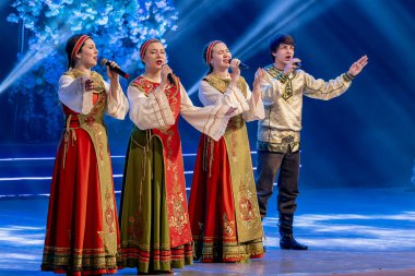 Ulusal Rus kostümleriyle düzenlenen festival konserinde performans. Erkekler ve kadınlar sahnede ulusal şarkılar söylüyorlar..