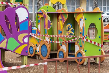 Çocuk parkı yasaklayıcı bir sinyal bandıyla kapatılmış. Koronavirüs salgını sırasında çocuklar dışarıda oynayamaz. COVID-19.