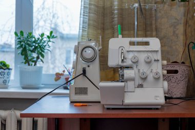 Bir terzinin, moda tasarımcısının, inşaatçının işyeri. Masada iki dikiş makinesi var..