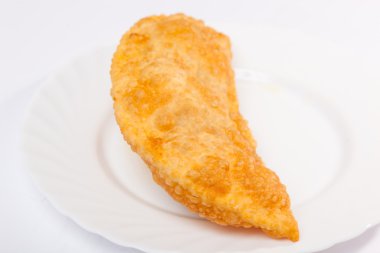 Bir cheburek, beyaz tabakta kuzu eti