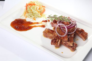 Soslu domuz kaburgası ve tabakta biberiye.