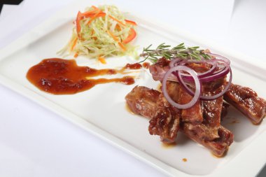 Soslu domuz kaburgası ve tabakta biberiye.