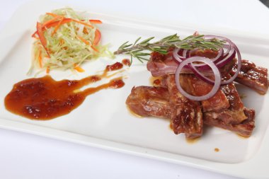 Soslu domuz kaburgası ve tabakta biberiye.